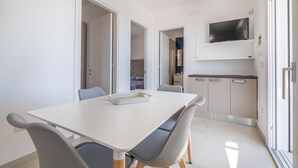 Una cocina moderna con armarios blancos, un horno empotrado y un televisor de pantalla plana sobre la encimera.