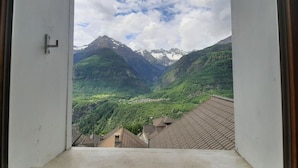 A view from a window overlooking a valley with mountains and a small village. - Two-bedroom apartment with mountain view and garden (SANTORINI) (Anzonico)