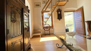 A spacious room with a wooden floor, a glass table, and a staircase leading to another level. - Two-bedroom apartment with mountain view and garden (SANTORINI) (Anzonico)