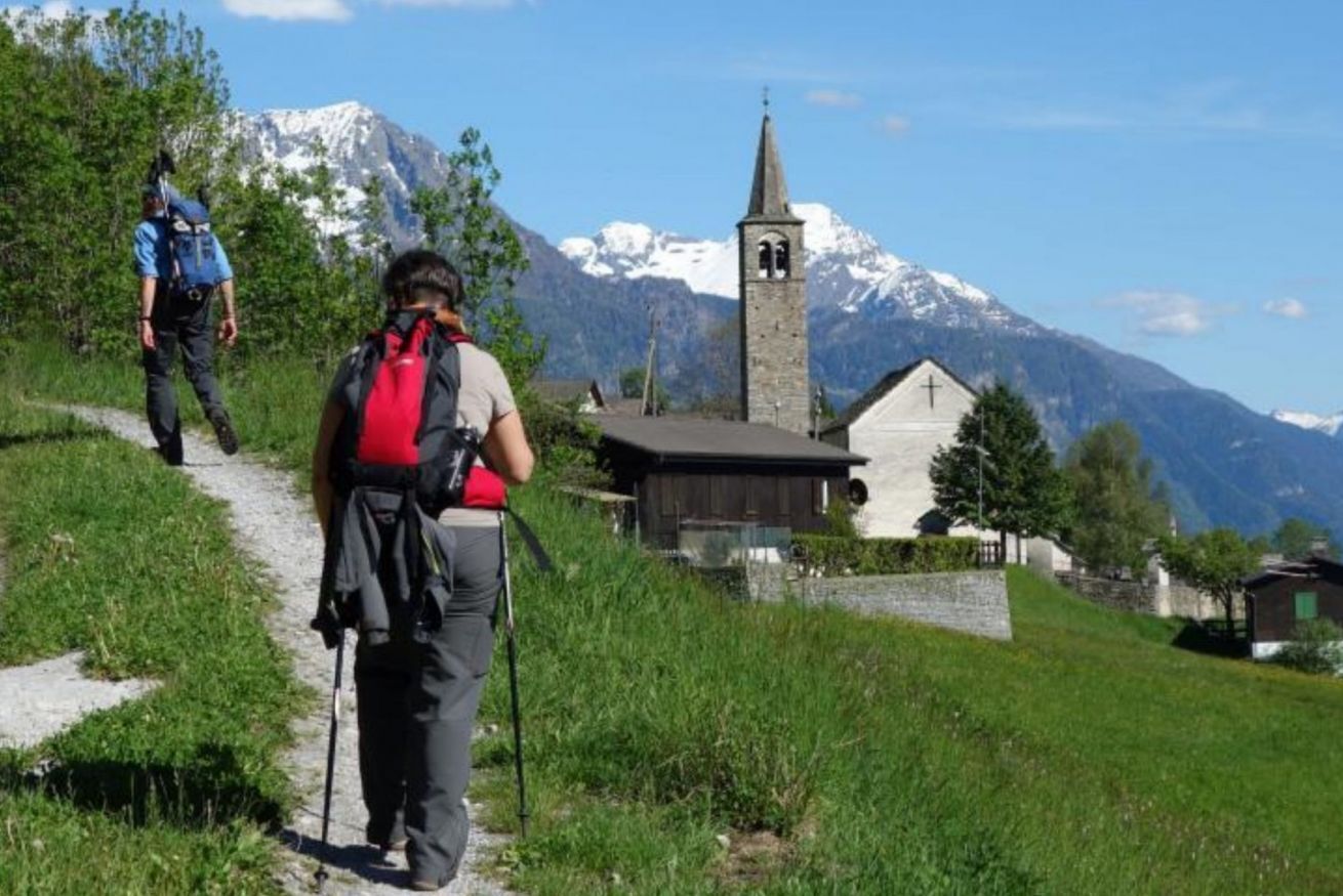 Un sentiero escursionistico con una chiesa e montagne sullo sfondo.