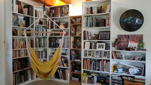 A room with a large bookshelf filled with books and a hammock.