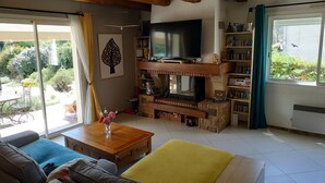 A cozy living room with a fireplace, a television, and a bookshelf.