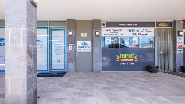 A building entrance with a sign for 'Surfside Apartments' and a 'Friendly Grocer' store. - Villa Serene 3, 6-10 Market Street -  Surfside Apartments WiFi, water views, Air Con,  Pool (Fingal Bay)