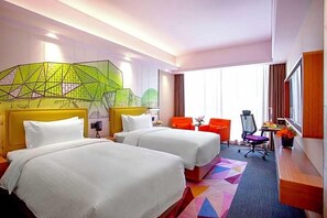 Habitación de hotel con dos camas, un escritorio, una silla y un ventanal grande.