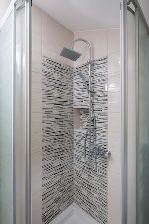 A glass-enclosed shower with a modern design, featuring a rain showerhead and handheld showerhead, and a tiled wall with a black and white pattern. - A8 - Modern apt With Terrace, 3 min Walk to Beach (Marina)