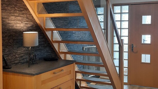 Een houten trap met een stenen muur en een kast.