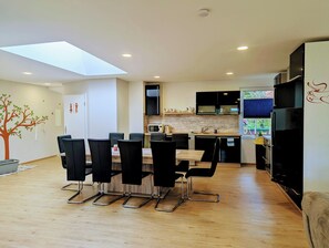 A modern kitchen with a dining area, featuring a skylight, wooden flooring, and contemporary appliances. - Ferienwohnung Harnisch (Aue-Bad Schlema)