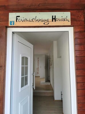 A wooden-framed doorway with a sign reading "Ferienswohnung Harnisch" and a Facebook icon. - Ferienwohnung Harnisch (Aue-Bad Schlema)
