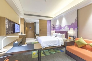 Une chambre d’hôtel équipée d’un lit, d’un canapé, d’un bureau, d’une télévision et d’une carte accrochée au mur.