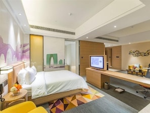 Une chambre d’hôtel avec un lit, un bureau et un téléviseur.