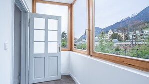 A room with a large window, a white door, and a view of a mountainous landscape.