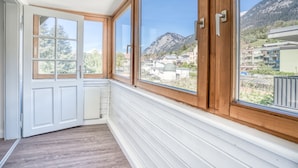 A room with large windows, white walls, and a wooden floor.