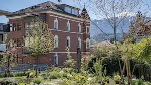 A multi-story building with a red facade, large windows, and a balcony.
