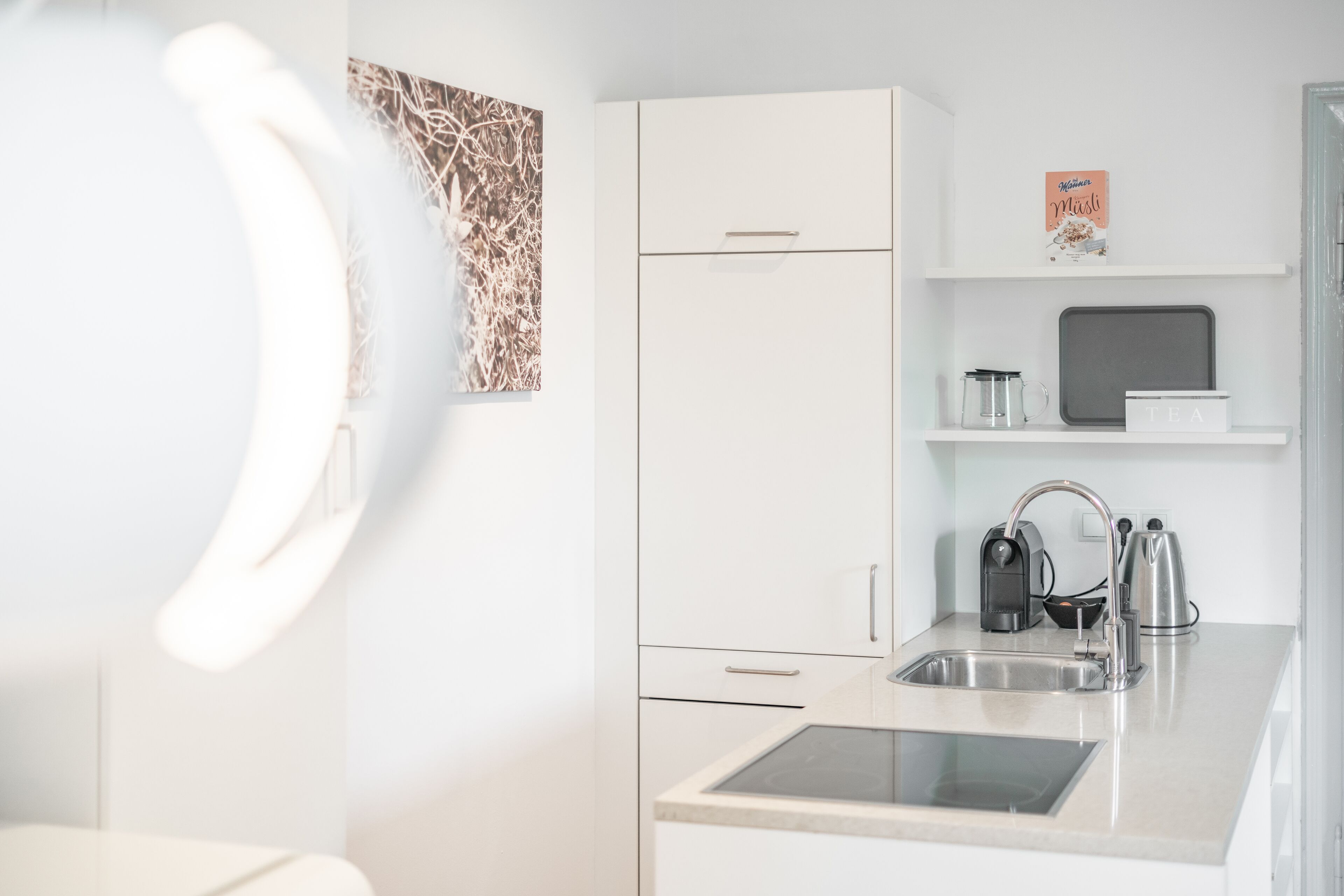Een moderne keuken met witte kasten, een roestvrijstalen spoelbak en een waterkoker.