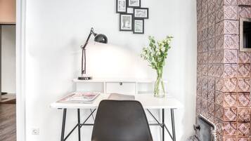A workspace with a desk, chair, lamp, and framed pictures on the wall.