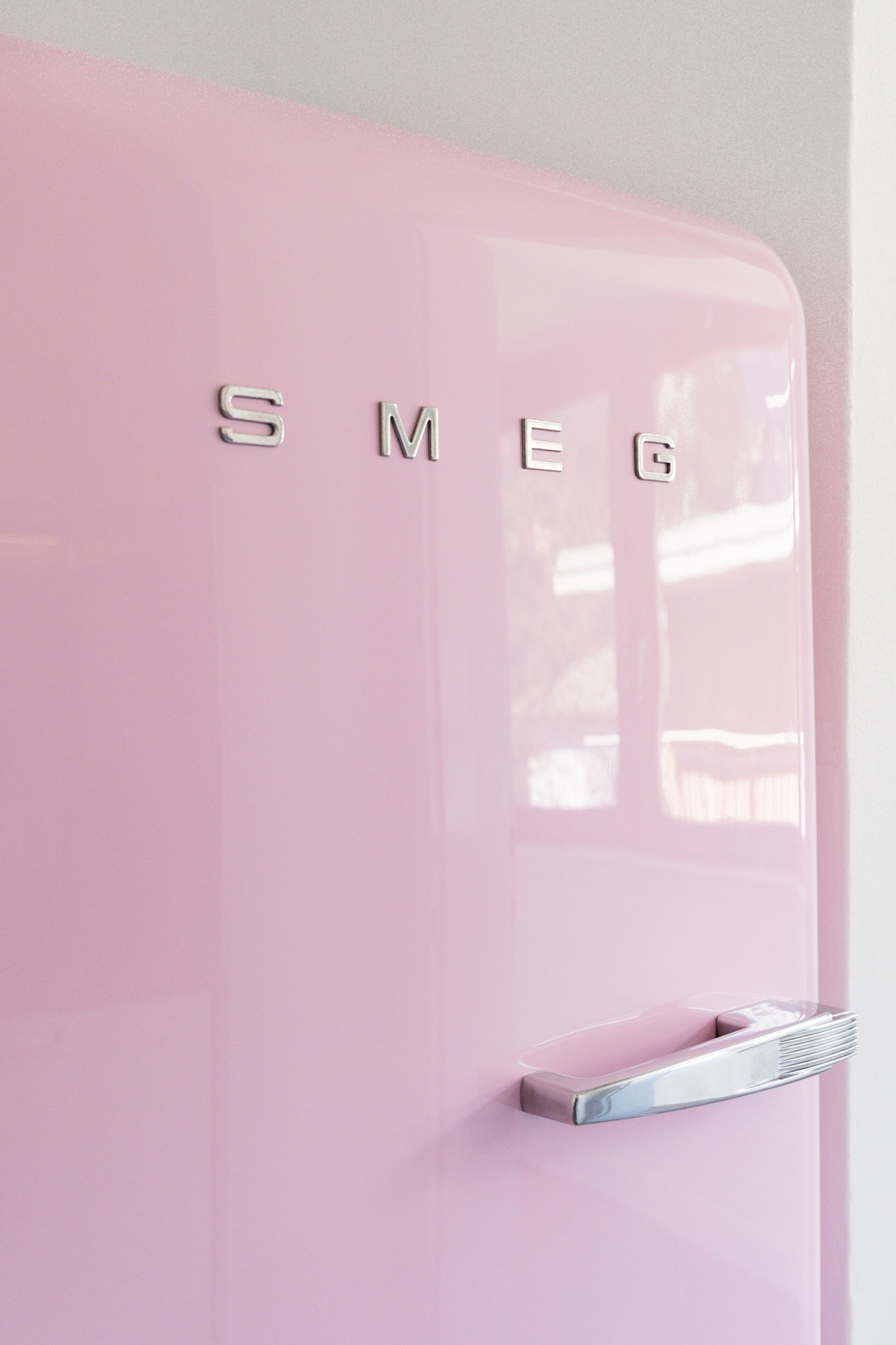 A pink refrigerator with the brand name "SMEG" on it.