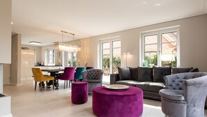 A spacious living room with a modern chandelier, a grey sofa set, and vibrant chairs. - Luxus-hausteil in Beliebter Wohngegend auf ca. 170 m² für bis zu 7 Personen (Wenningstedt-Braderup (Sylt))