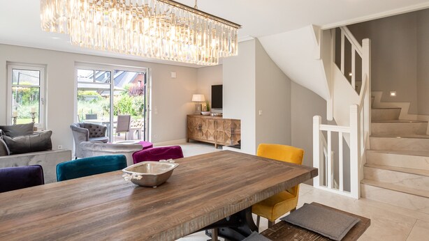 A modern dining area with a wooden table, colorful chairs, and a chandelier. - Luxus-hausteil in Beliebter Wohngegend auf ca. 170 m² für bis zu 7 Personen (Wenningstedt-Braderup (Sylt))