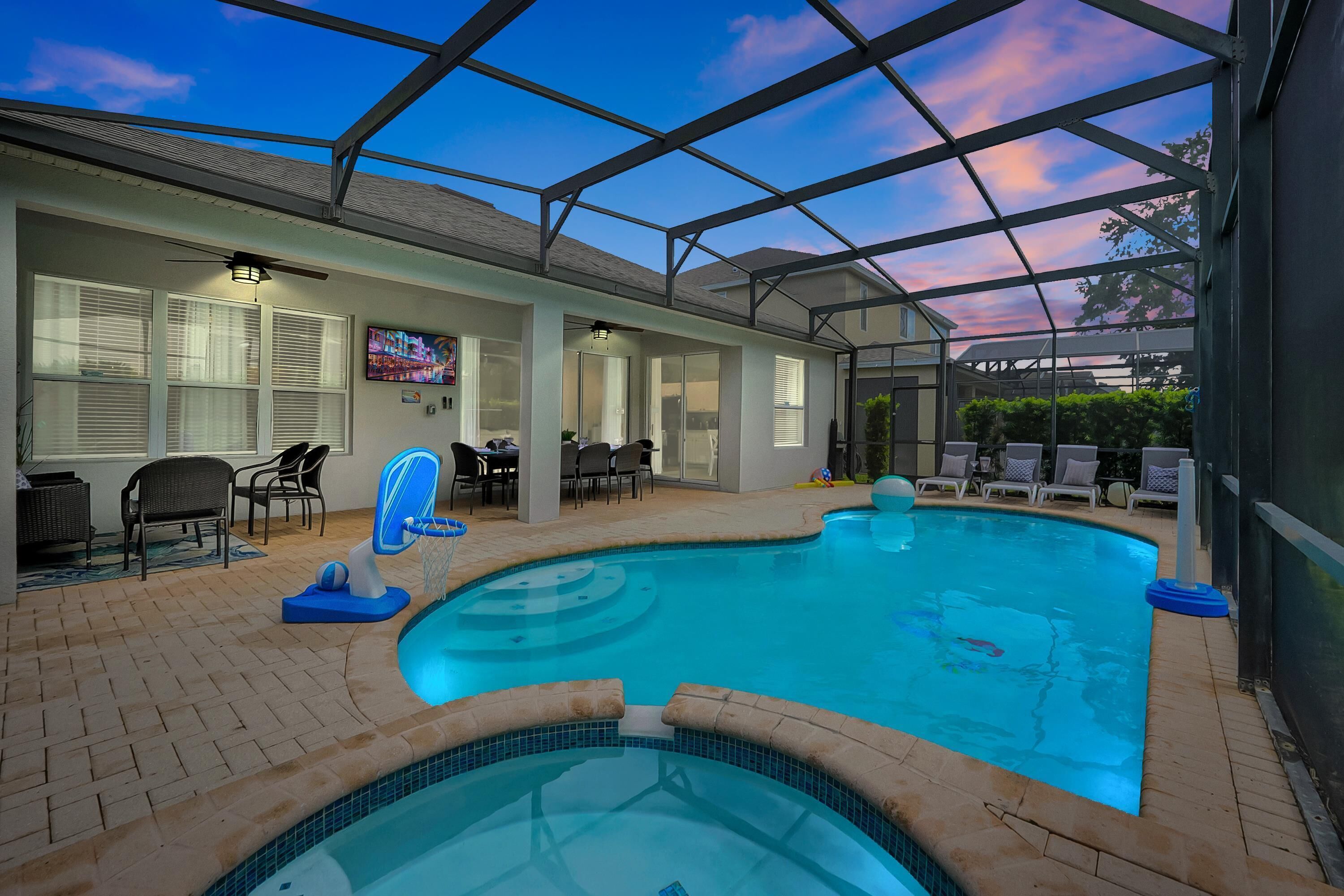 Una piscina interior con techo de cristal, sillones de descanso y televisor.