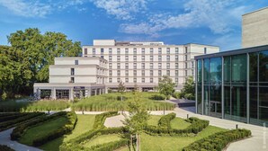 A modern hotel with a central courtyard, surrounded by neatly trimmed hedges and trees.
