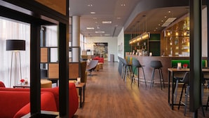 A modern bar area with a long counter, bar stools, and a variety of bottles.