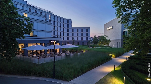 A modern hotel with outdoor seating and a well-maintained garden area.