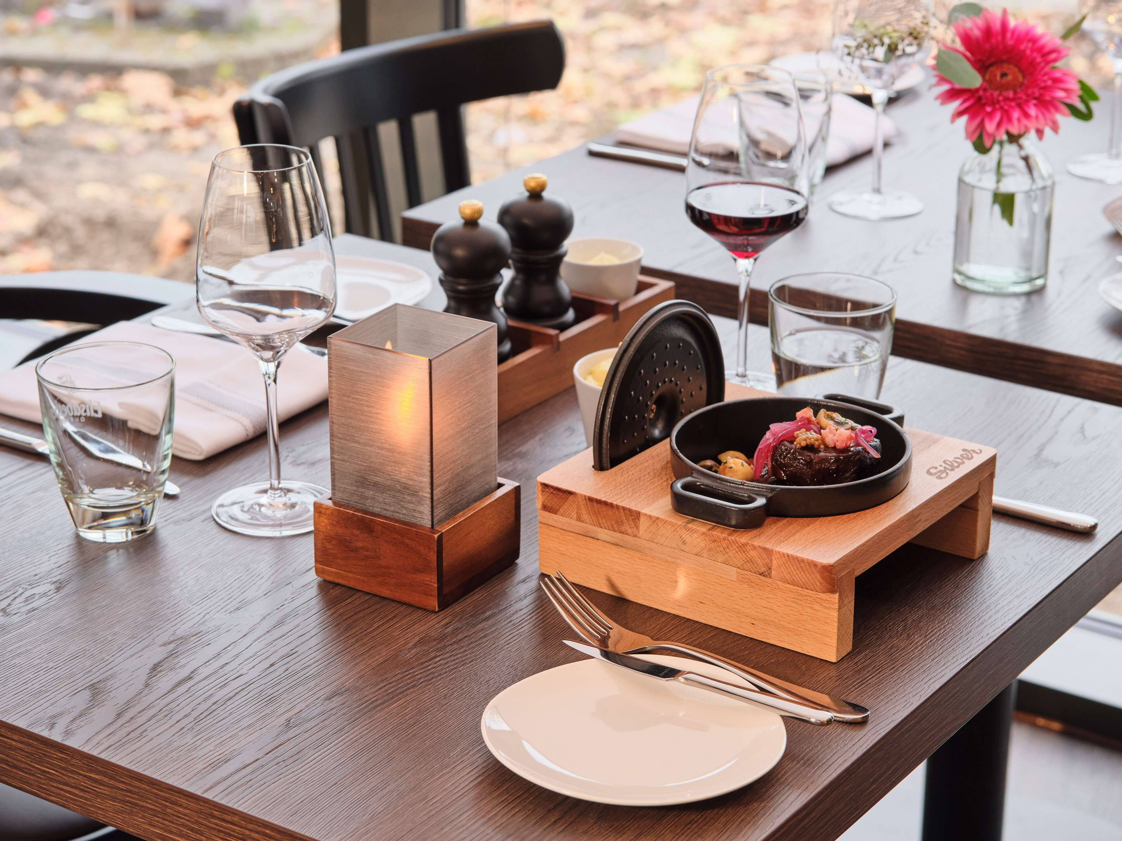 A dining table set with a candle, a bowl of food, and wine glasses.