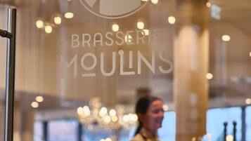 Interior de restaurante con una partición de vidrio, un logotipo y una persona con delantal.
