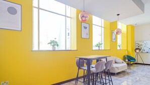 A bright yellow room with a table and chairs, large windows, and a floor lamp. - Belvilla Newport City Centre Hotel - Lifestyle (Newport)