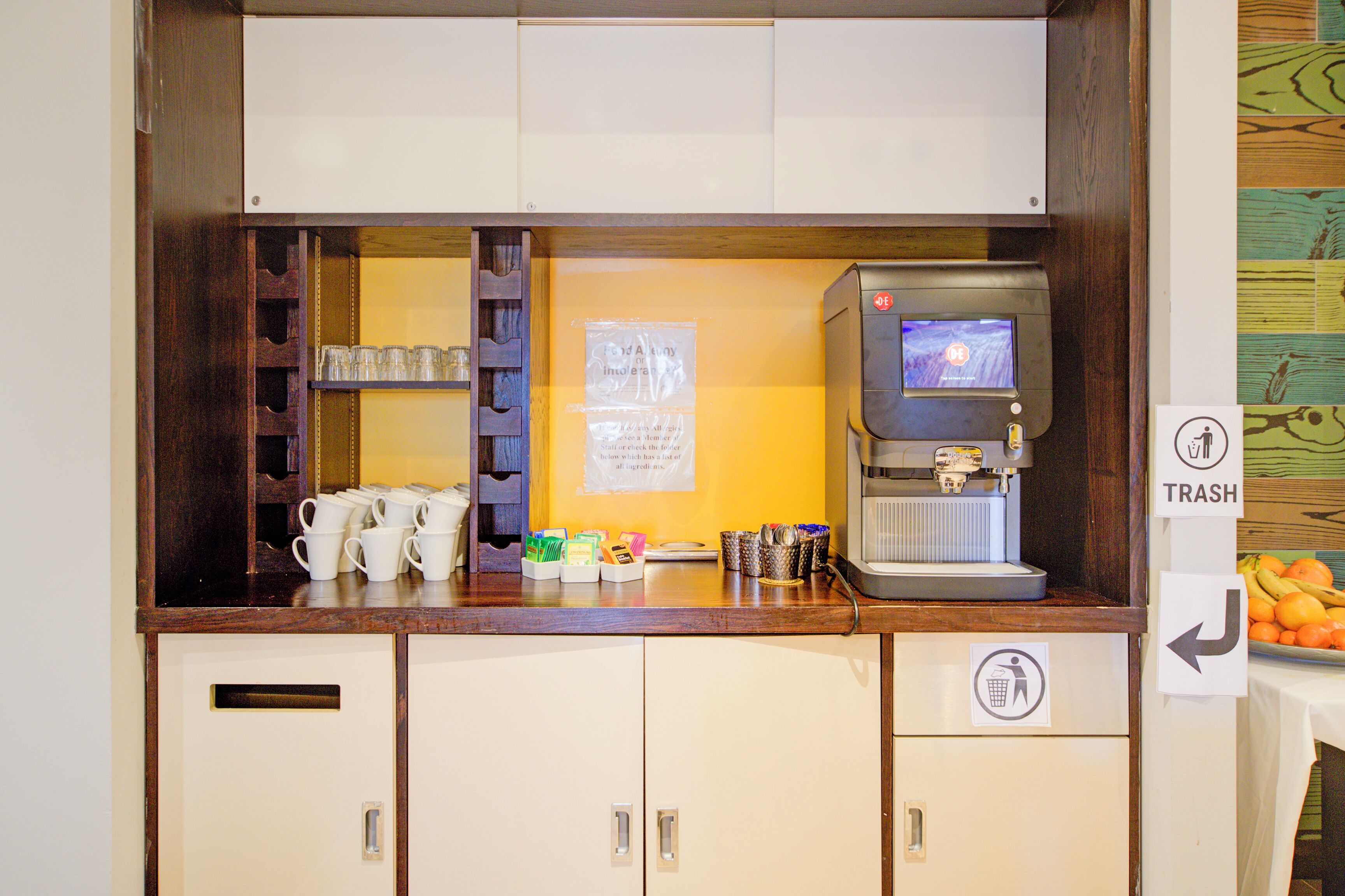 Un coin café équipé d’une machine à café, de tasses et d’une poubelle.