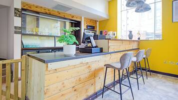 Un espace cuisine doté de meubles en bois, d’un comptoir-bar et de tabourets de bar.