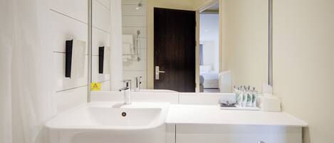 Un baño moderno con lavamanos, espejo y muebles blancos.