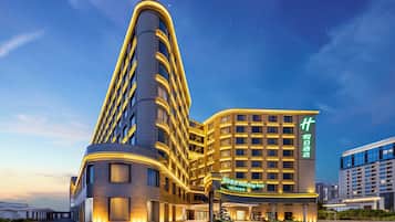 Un hotel moderno con fachada curva, ventanas iluminadas y un letrero destacado de Holiday Inn.