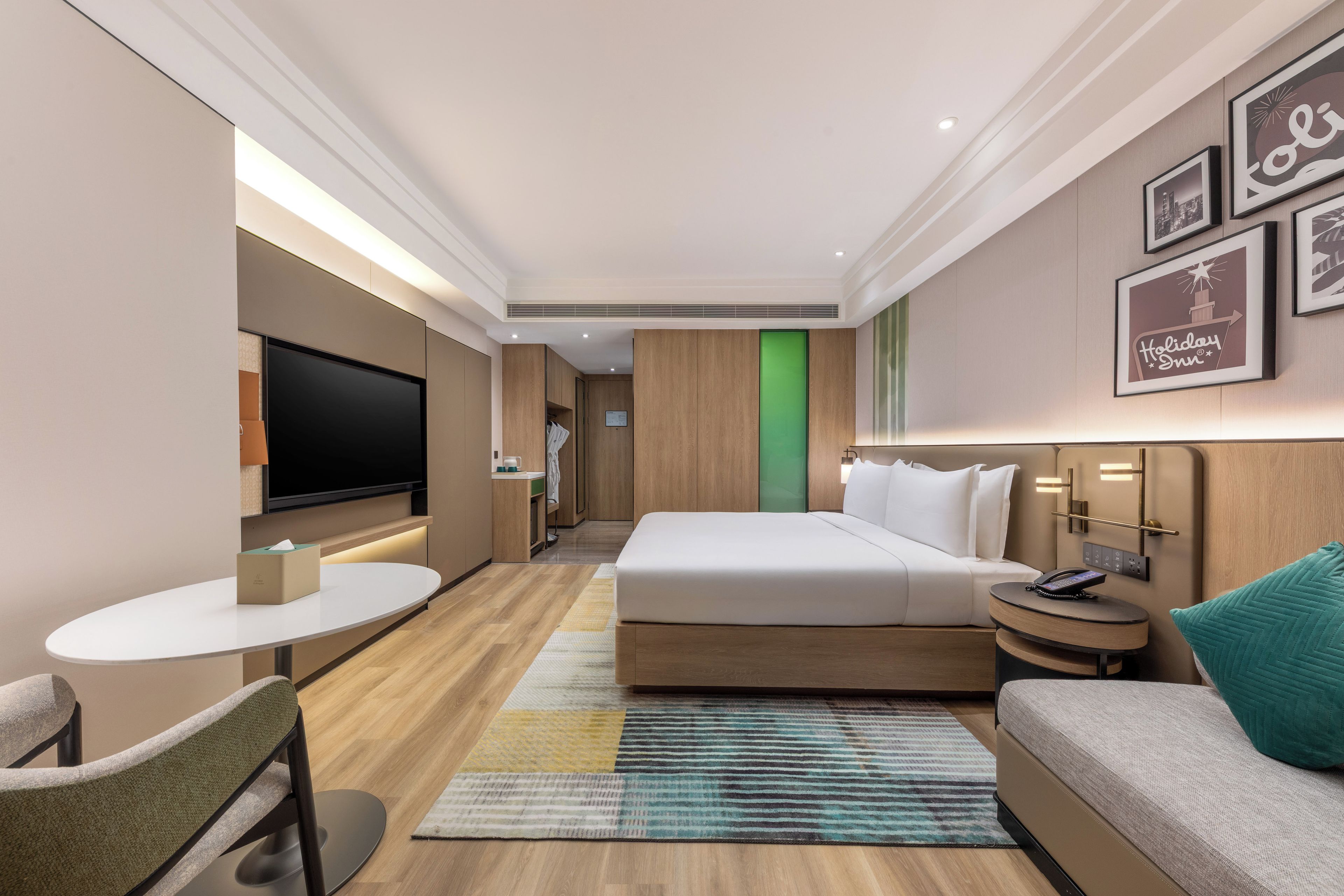 Een hotelkamer met een bed, een televisie, een bureau, een stoel en een bank.