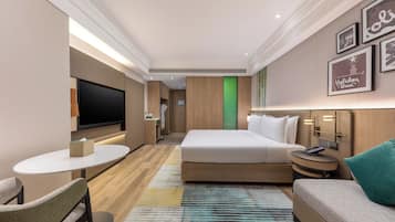 Een hotelkamer met een bed, een televisie, een bureau, een stoel en een bank.