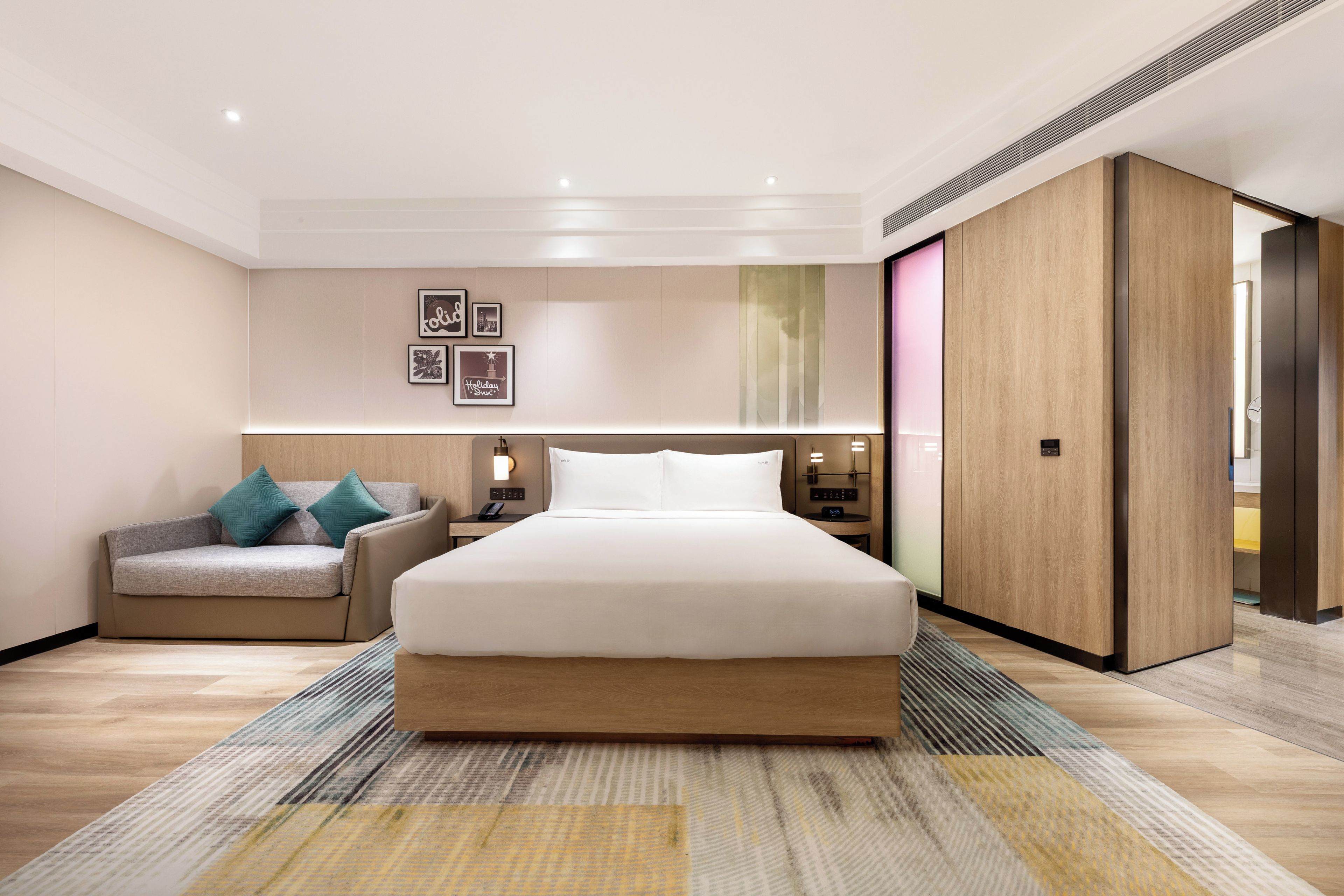 Een moderne hotelkamer met een groot bed, een bank, een nachtkastje en een kledingkast.