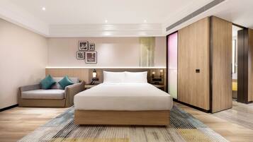 Een moderne hotelkamer met een groot bed, een bank, een nachtkastje en een kledingkast.