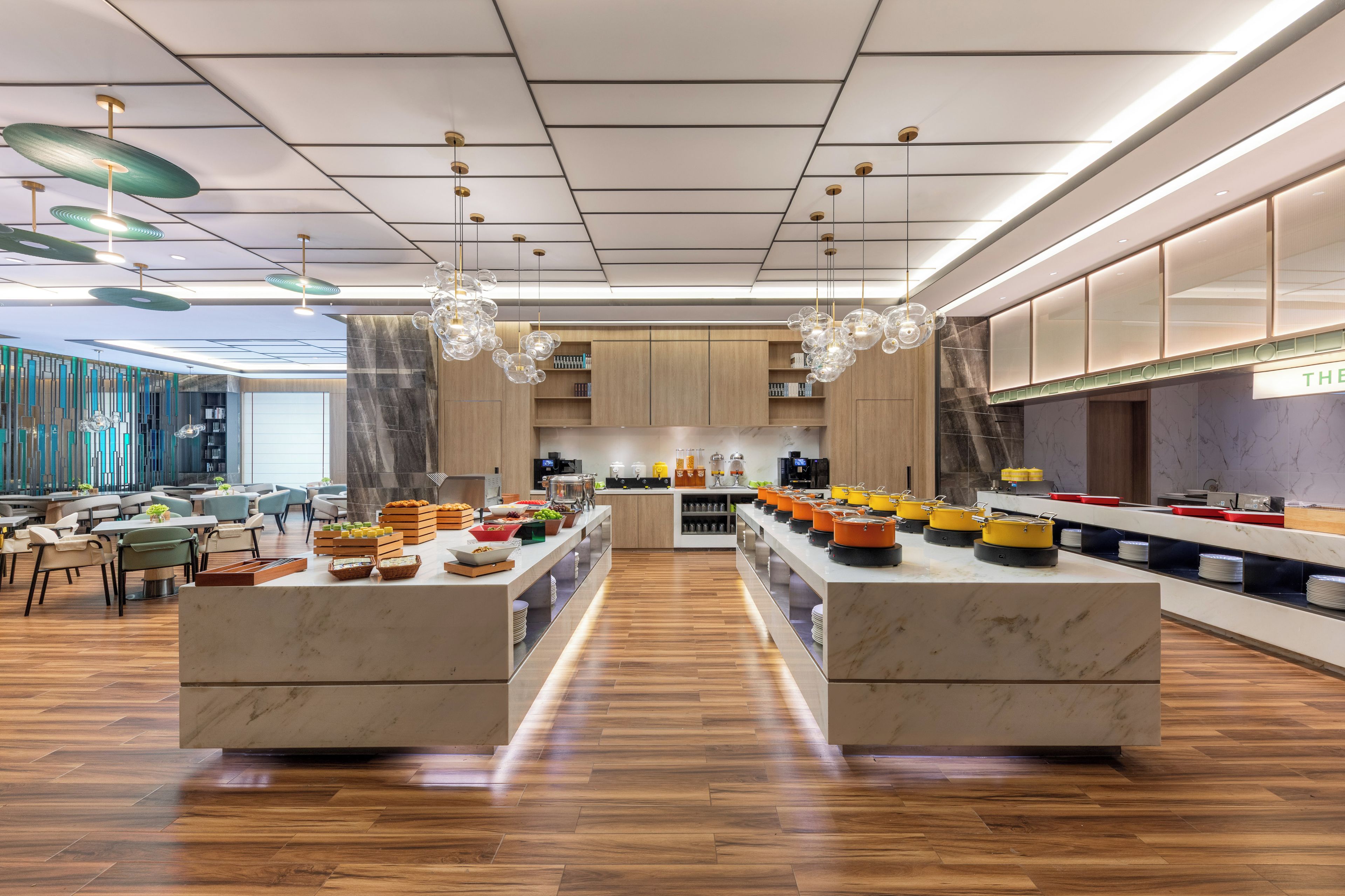 Un moderno vestíbulo de hotel con una isla central, suelo de madera y luminarias contemporáneas.