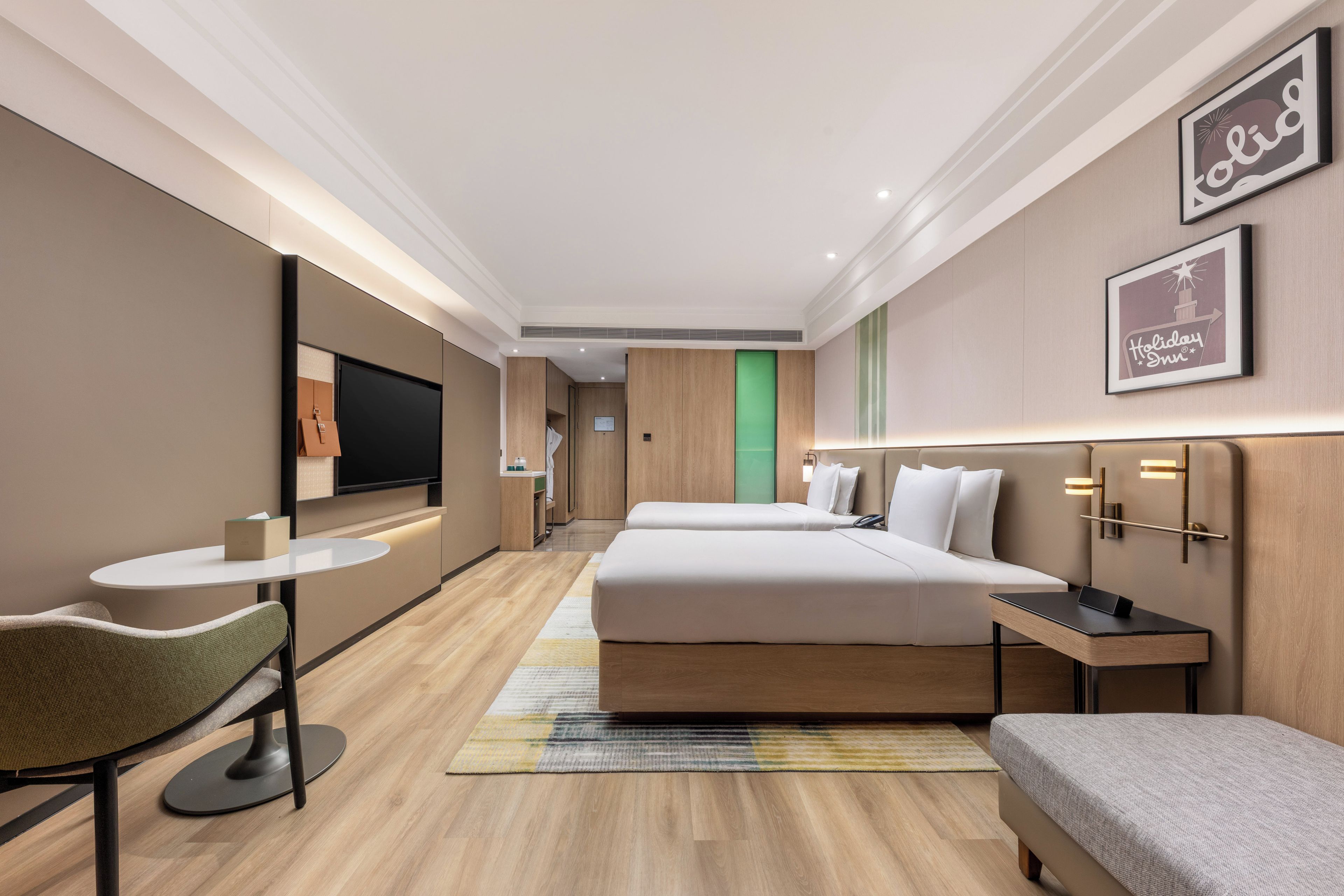 Habitación de hotel con cama, escritorio, silla, televisión y un cartel enmarcado en la pared.
