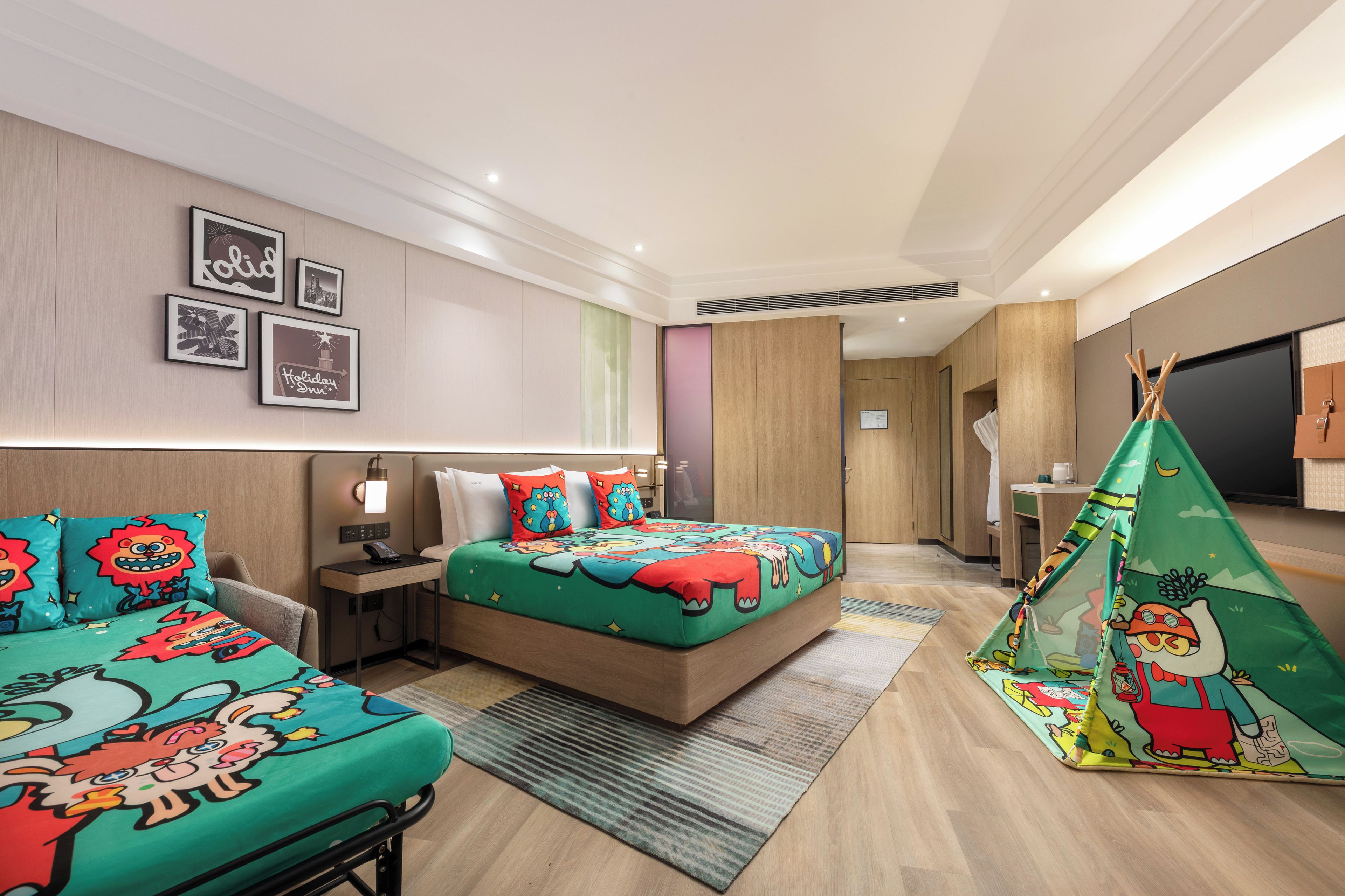 Una habitación de hotel con cama, mesita de noche, lámpara, televisor montado en la pared y una estructura parecida a una tienda de campaña.