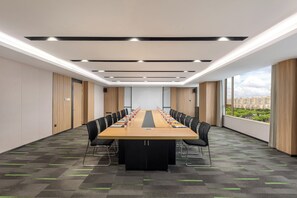 A conference room with a long table, chairs, and a city view through large windows.