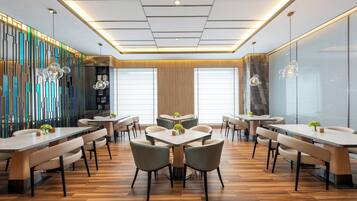 Un comedor moderno con varias mesas y sillas, una pared decorativa con paneles verticales e iluminación empotrada en el techo.