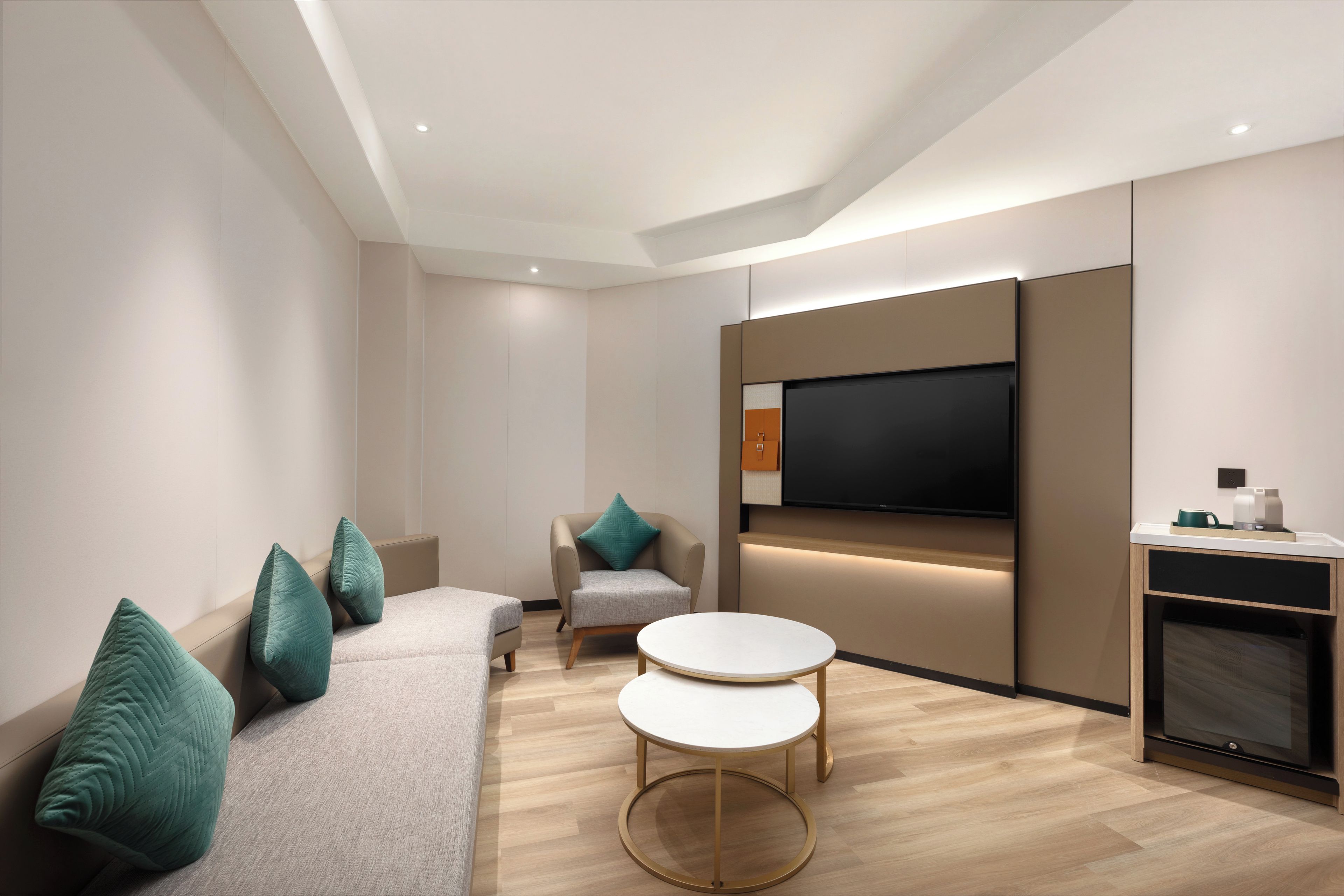 Una sala de estar moderna con un sofá, dos sillones, una mesa de centro y un televisor de pantalla plana montado en la pared.