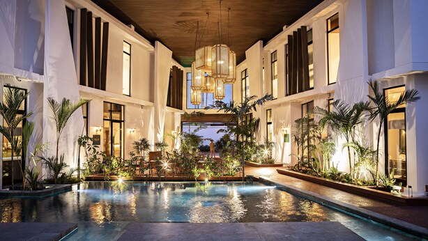 Un área de piscina con techo de madera, ventanas amplias y plantas de interior.