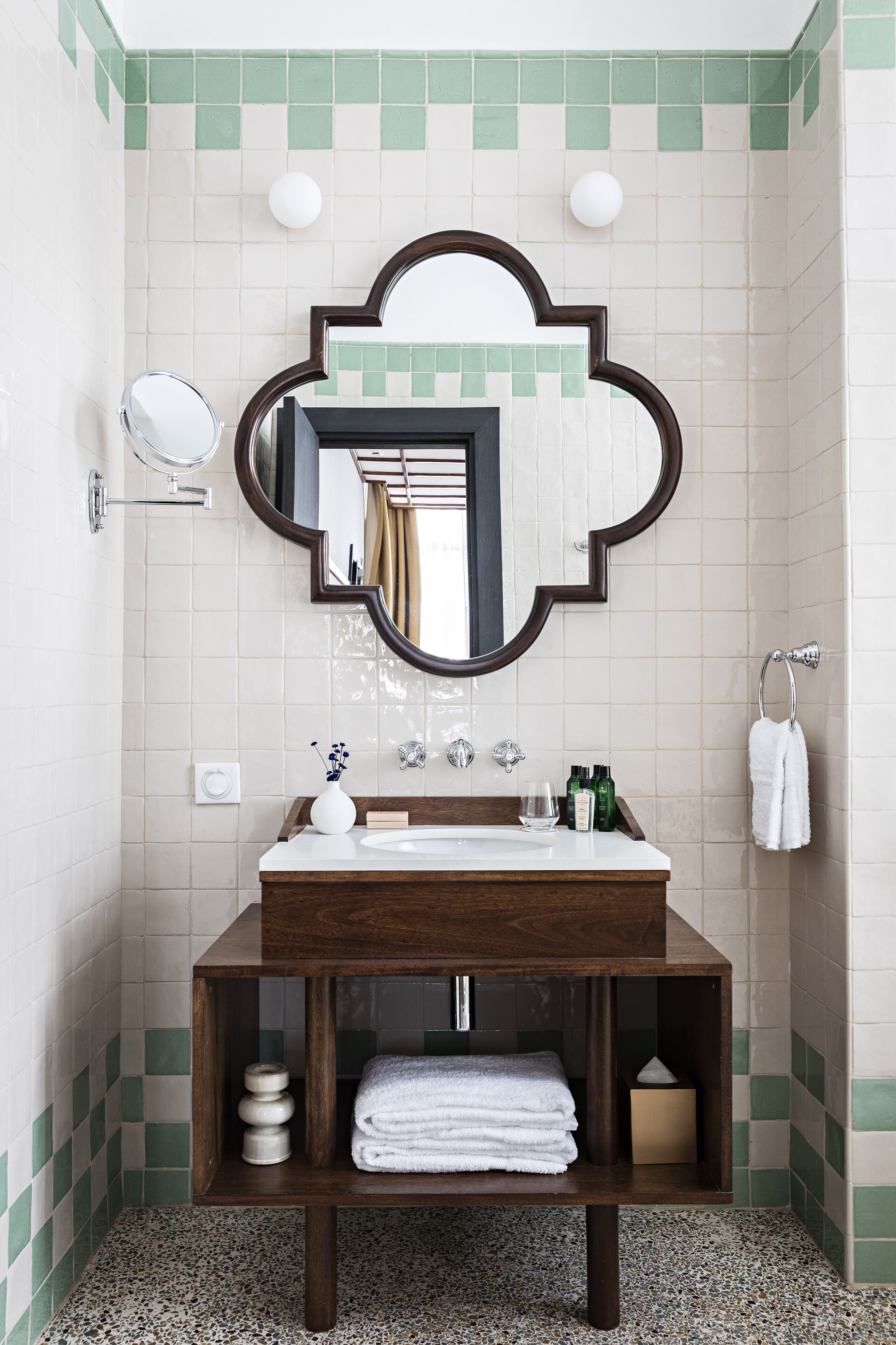 A bathroom with a wooden vanity, a large mirror, and a tiled wall.