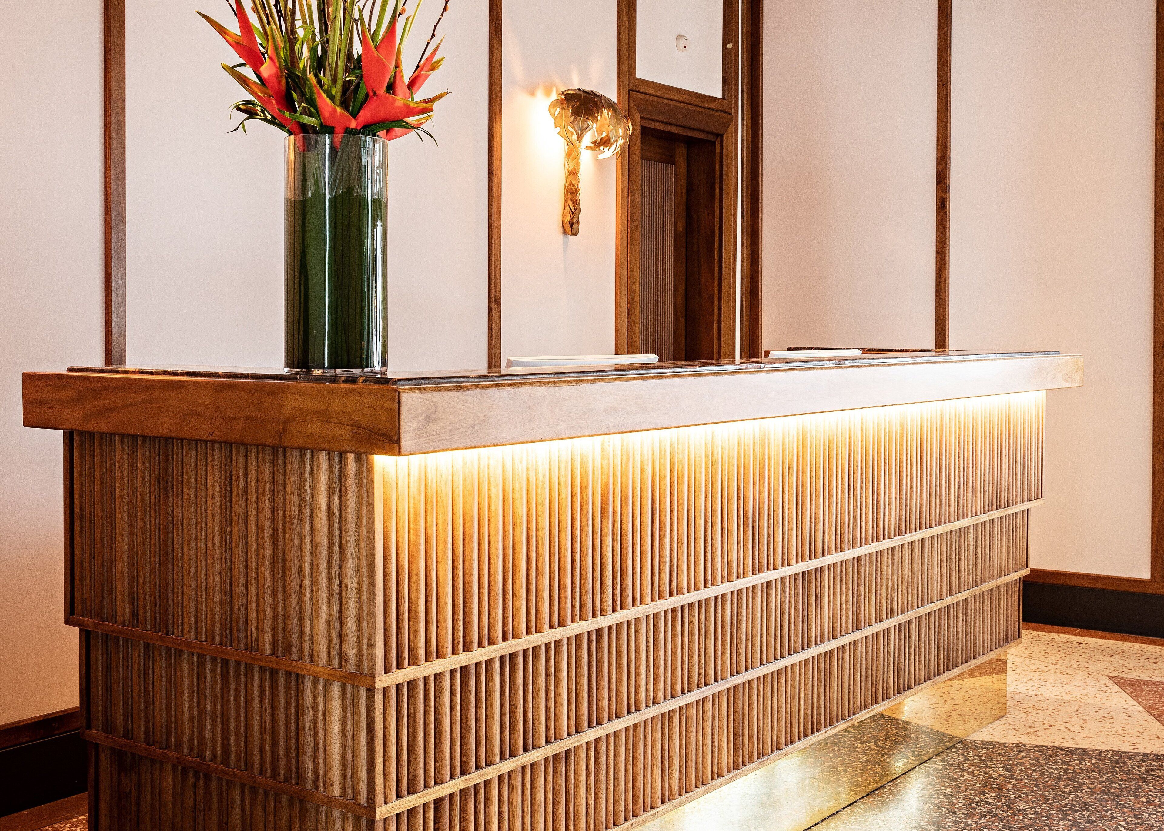 Un mostrador de recepción con acabado de madera y paneles verticales.