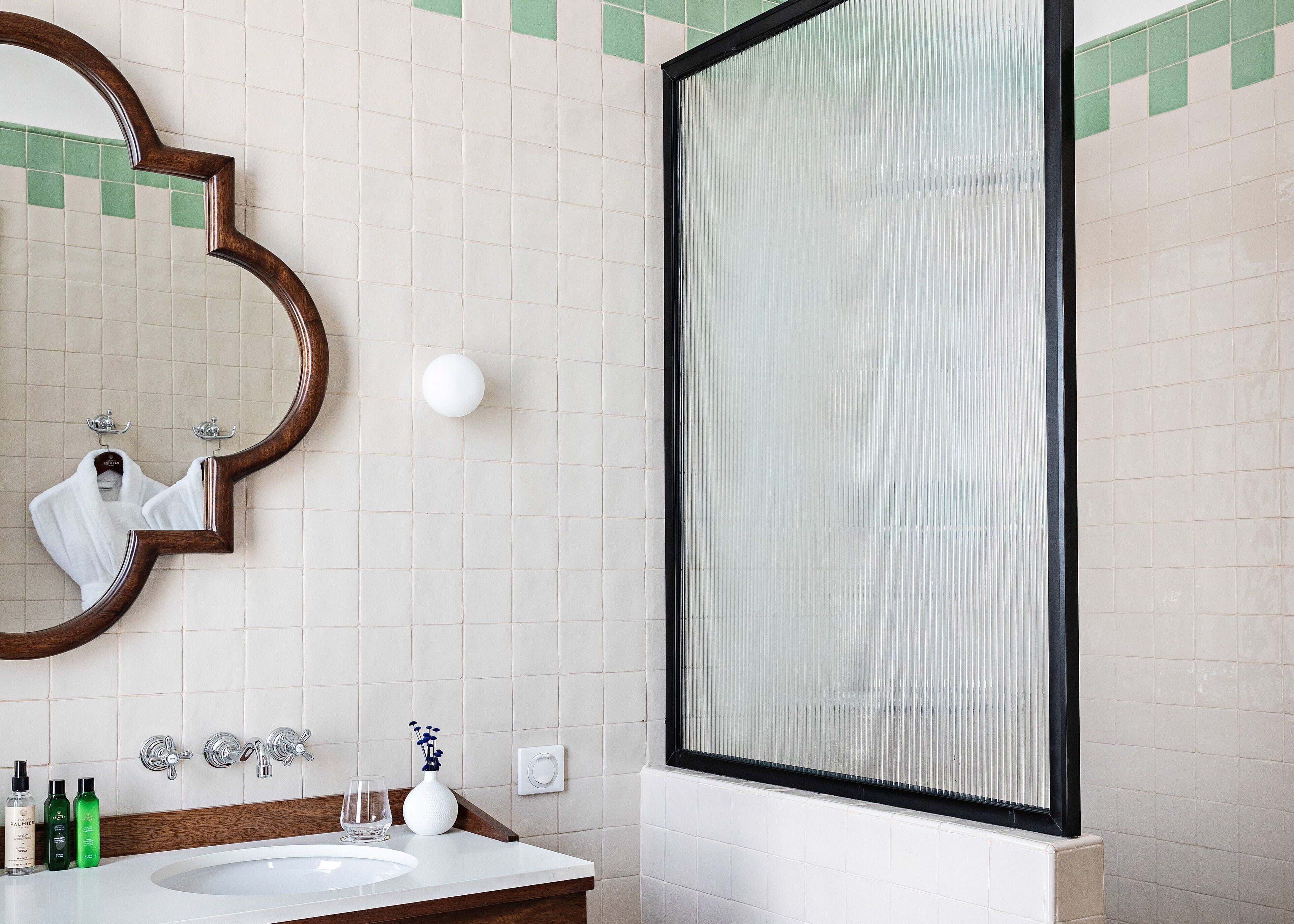 A bathroom with a large mirror, a sink, and a shower area.