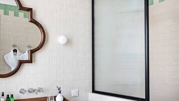 A bathroom with a large mirror, a sink, and a shower area.