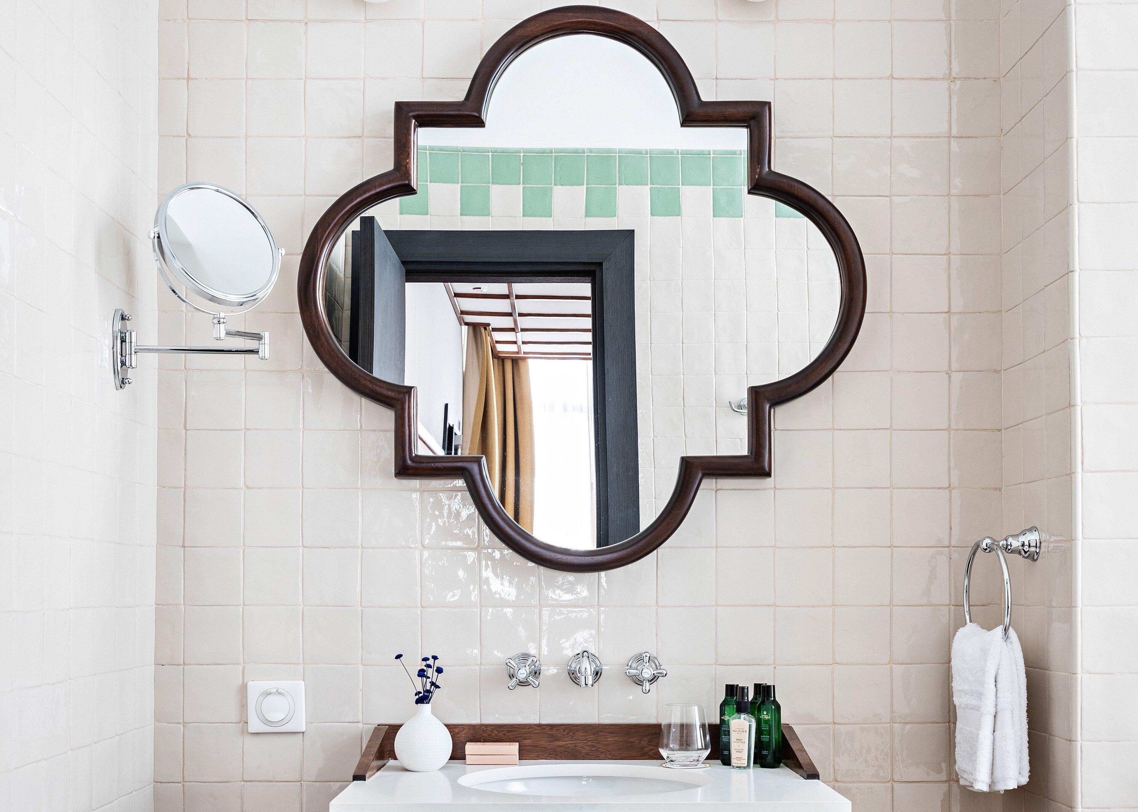 A bathroom with a large mirror, a sink, a towel rack, and toiletries.