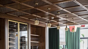 Una zona de bar con una barra larga, varios taburetes y un techo de vigas de madera.